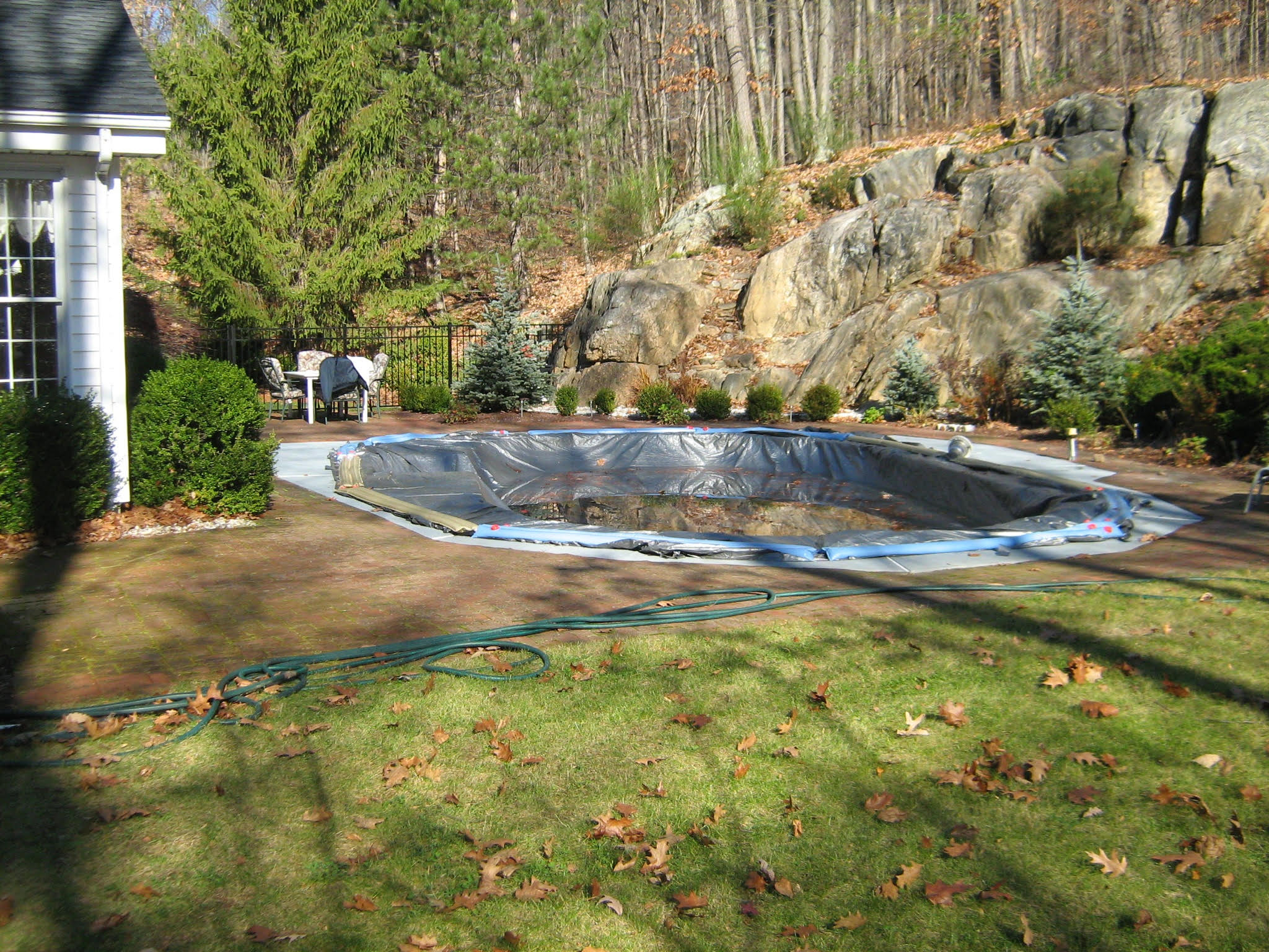 Before pool setting with older deck conditions and outdoor furniture near the water